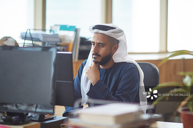 戴着库非耶帽的商人正在办公桌前使用电脑图片素材