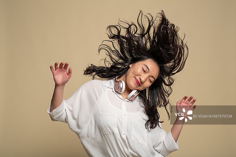 一位年轻的亚洲女孩正在听音乐图片素材