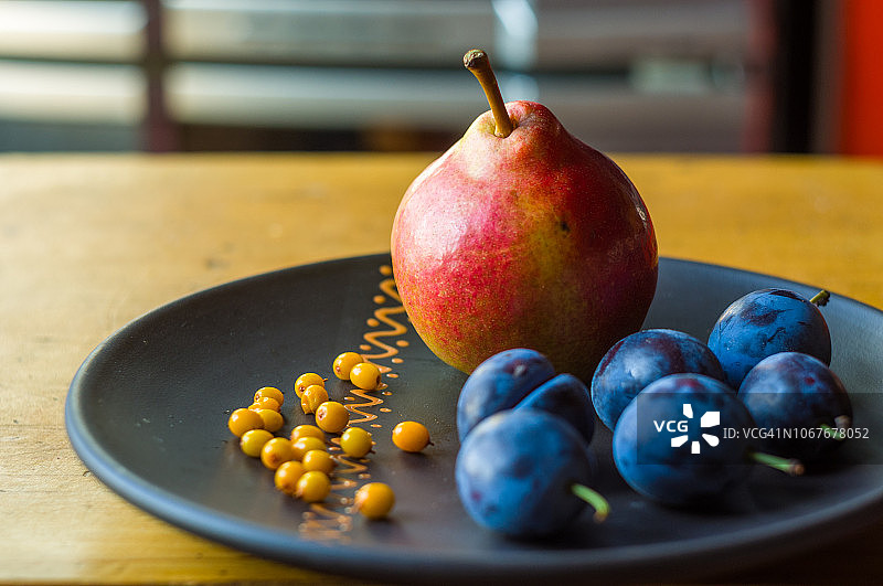 静物摄影 - 陶瓷盘中的蓝李子、梨和沙棘图片素材