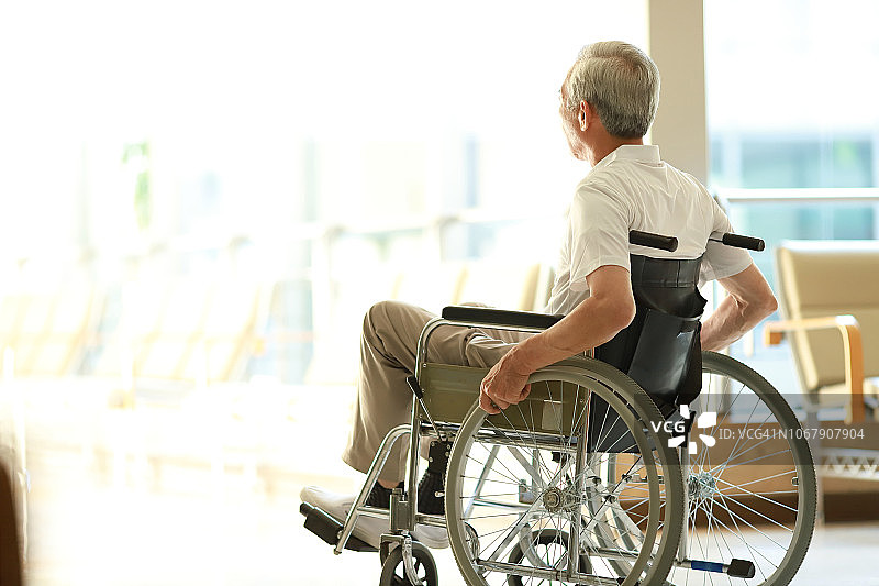 坐在轮椅上，望向窗外的老年男人图片素材
