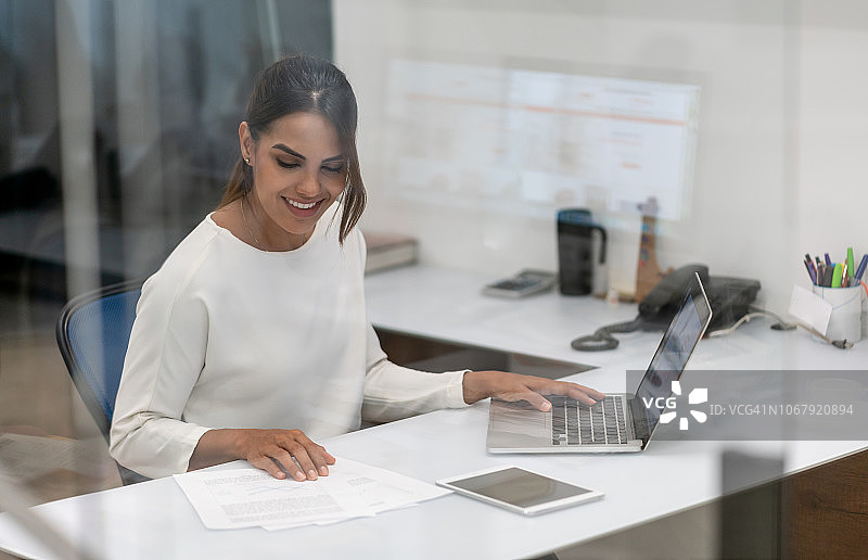自信的女商人使用笔记本电脑在办公室工作图片素材