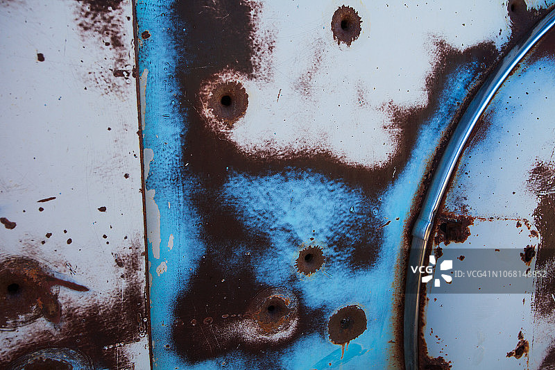 沙漠景观中废弃牧场上一辆生锈的20世纪30年代老式汽车的特写镜头，带有弹孔图片素材