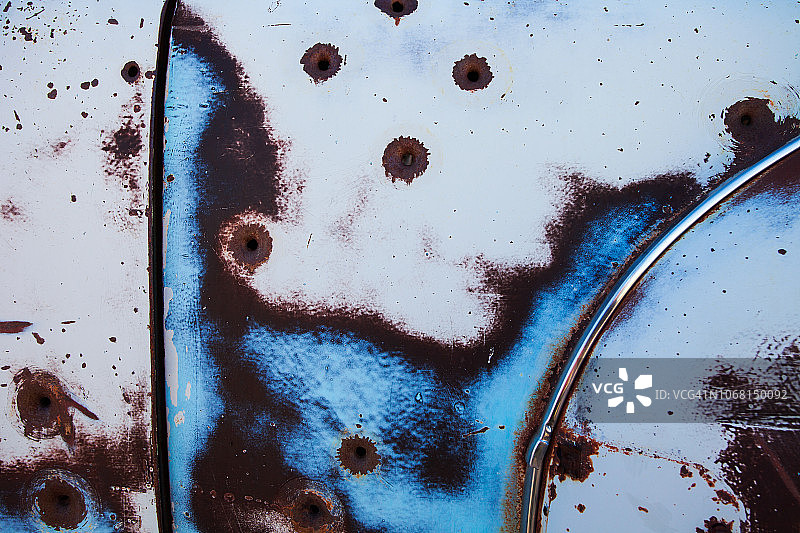 沙漠景观中废弃牧场上一辆生锈的20世纪30年代老式汽车的特写镜头，带有弹孔图片素材