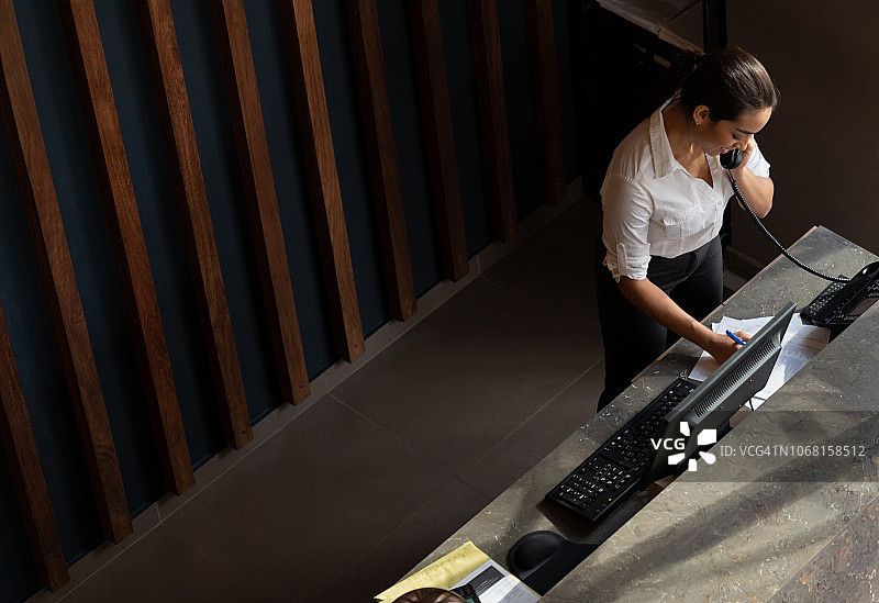 酒店友好的接待员接听客人电话的俯视图图片素材