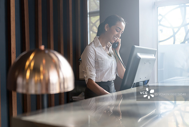 美丽友好的宾馆接待员接听客人的电话图片素材