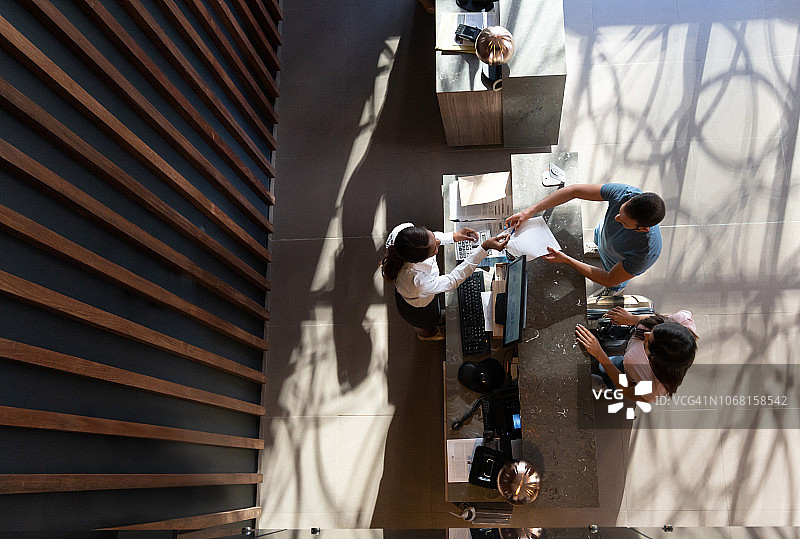 友好的接待员在豪华酒店向办理入住的男客人及其伴侣递交表格图片素材