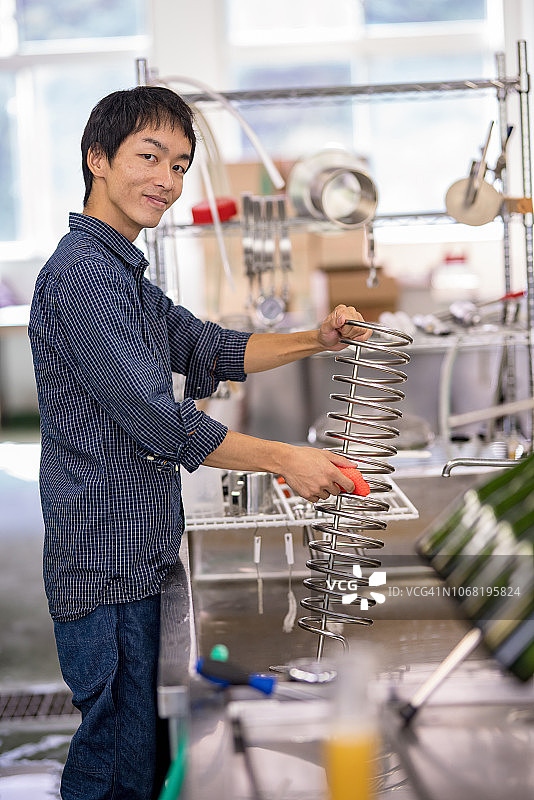 中年男人在小型精酿啤酒厂清洗啤酒酿造设备图片素材