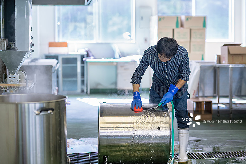 中年男人在小型精酿啤酒厂清洗啤酒酿造设备图片素材