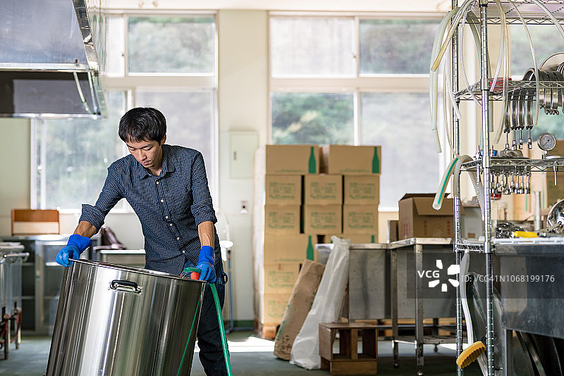 中年男人在小型精酿啤酒厂清洗啤酒酿造设备图片素材