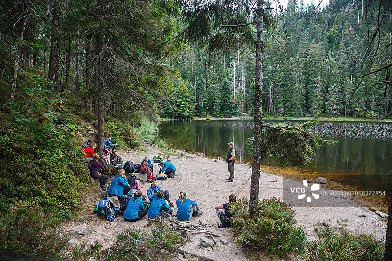 一群年轻探险者在湖边享受树木繁茂的环境图片素材