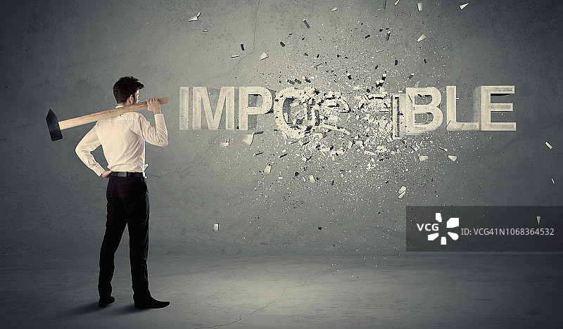 商务男士用锤子击打“不可能”标志图片素材