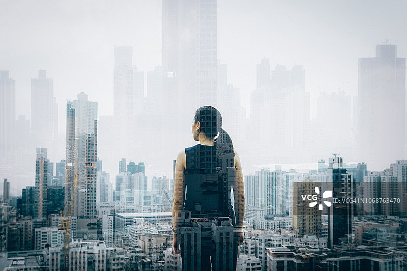 自信的年轻女子与香港城市天际线的鸟瞰图的双重曝光图片素材