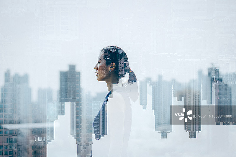 自信的亚洲女性与城市景观的双重曝光图片素材