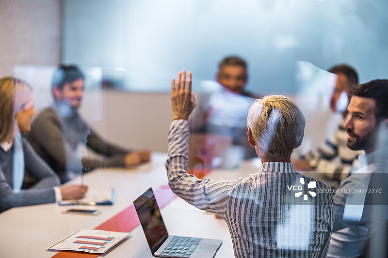 在会议室开会时举起手臂的女商人背面图图片素材