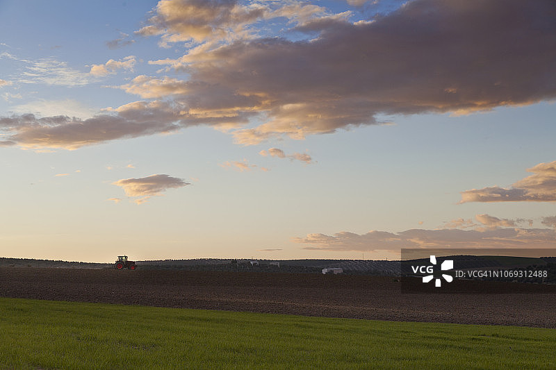 安达卢西亚田野的日落景观和耕地的拖拉机图片素材