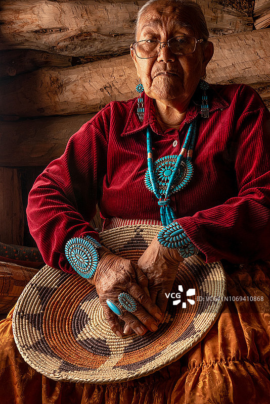 在传统霍根屋内摆姿势的美丽的85岁纳瓦霍族美国原住民老妇人图片素材