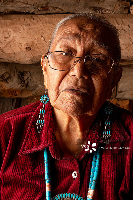 在传统霍根屋内摆姿势的美丽的85岁纳瓦霍族美国原住民老妇人图片素材
