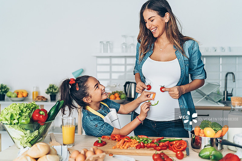 孕妇妈妈和女儿制作蔬菜笑脸图片素材
