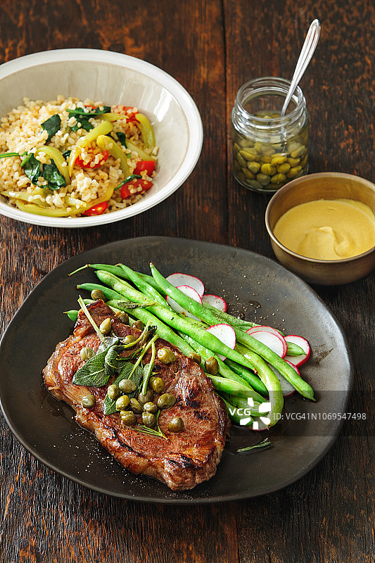 搭配芥末酱、蔬菜、香草和刺山柑的牛排图片素材