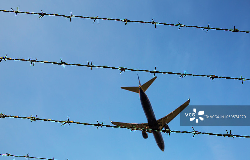 勃兰登堡舍内费尔德机场上空的带刺铁丝网和客机图片素材