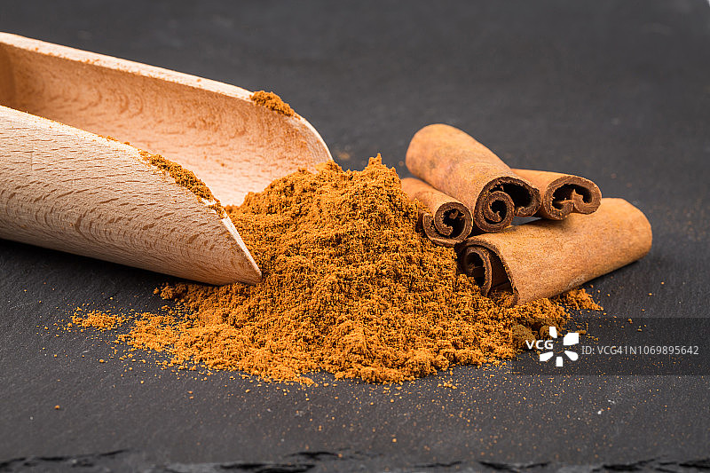 深色石板上的肉桂棒与粉末图片素材