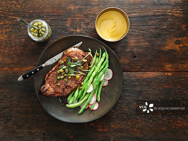 搭配芥末酱、蔬菜、香草和刺山柑的牛排图片素材