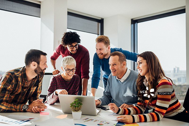 快乐的同事使用笔记本电脑图片素材