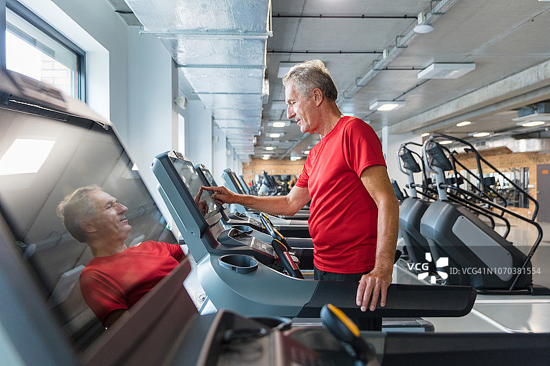 在康复中心跑步机上调整速度的老年男人图片素材