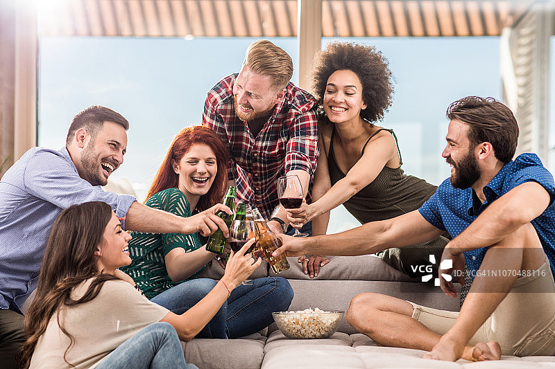 在客厅里敬酒的年轻无忧无虑的人们图片素材