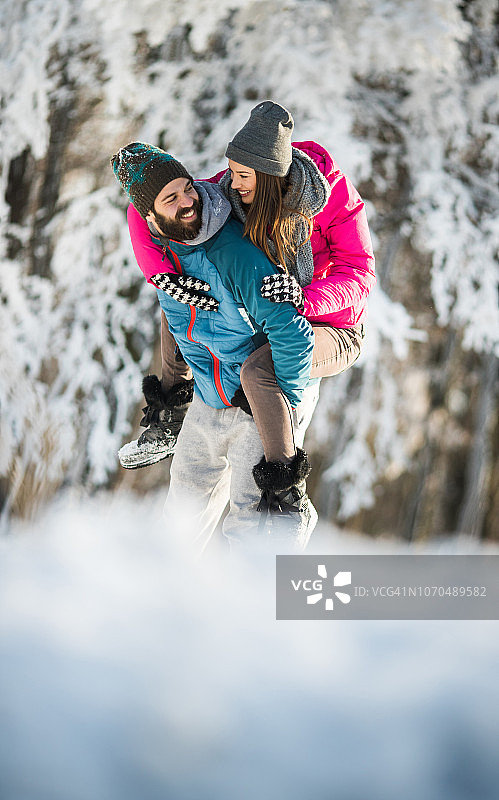 在冬日公园里无忧无虑地玩背背的年轻夫妇图片素材