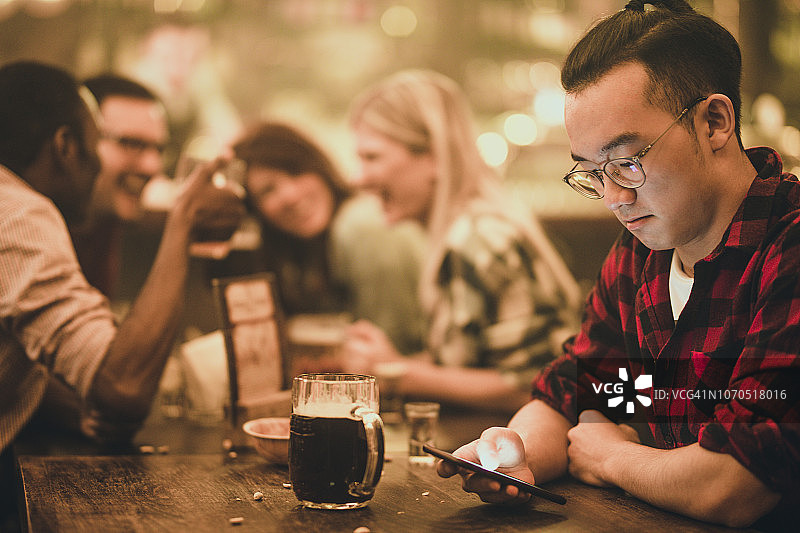 在酒吧夜晚使用手机的亚洲男人图片素材