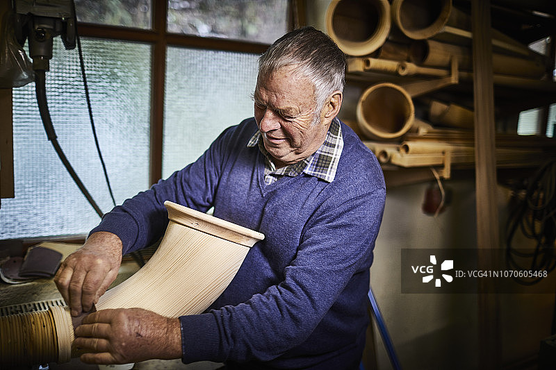 在工作室用砂纸制作阿尔卑斯号角的年长男人图片素材