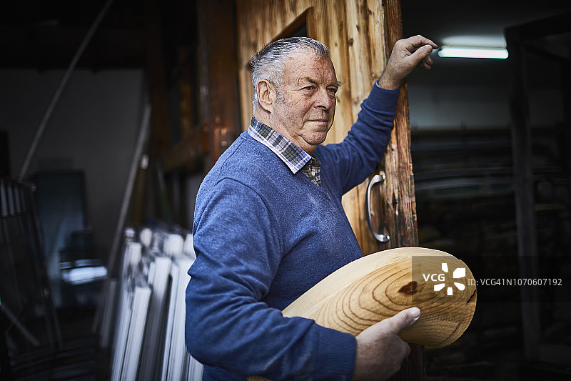 在工作室制作阿尔卑斯长号，手持乐器部件的年长男人图片素材