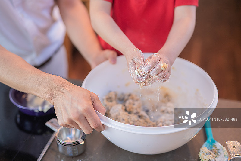 一位年轻的西班牙裔男孩帮助他的爸爸烤饼干图片素材