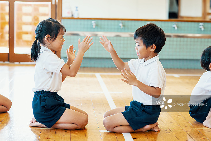 幼儿园里，小男孩和小女孩玩着有节奏的拍手游戏图片素材