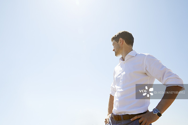 蓝天下穿白衬衫的年轻男子图片素材