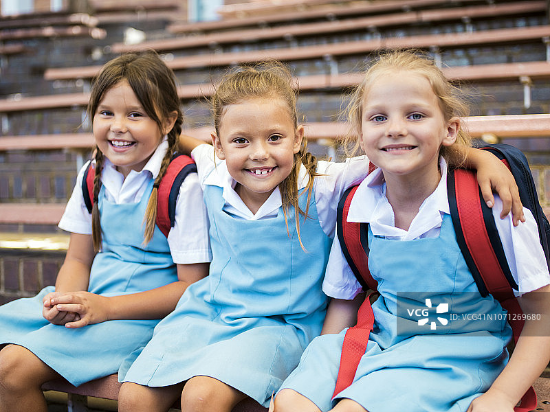 快乐的女孩坐在学校外的台阶上图片素材