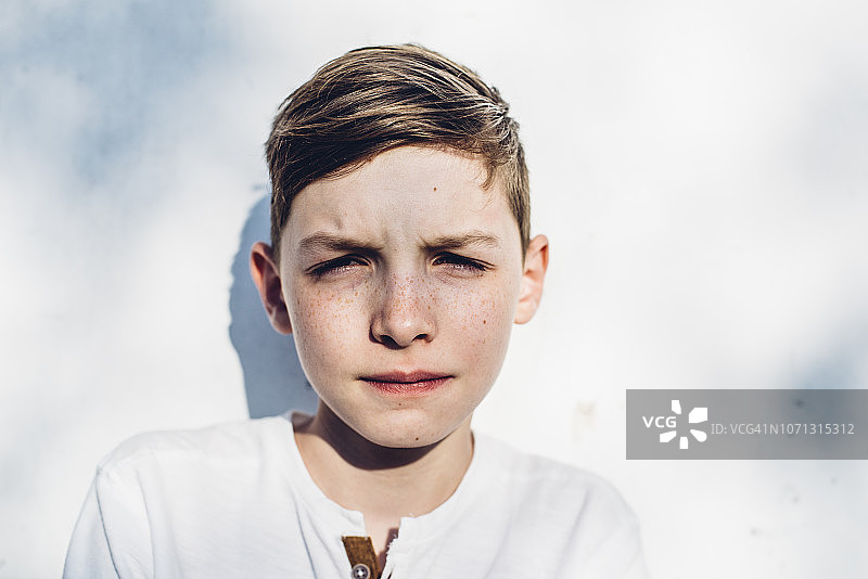 阳光下眯着眼睛的青少年男孩图片素材