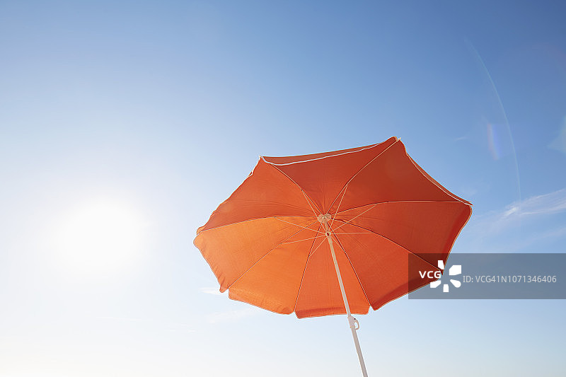 蓝色天空下的海滩橙色阳伞图片素材