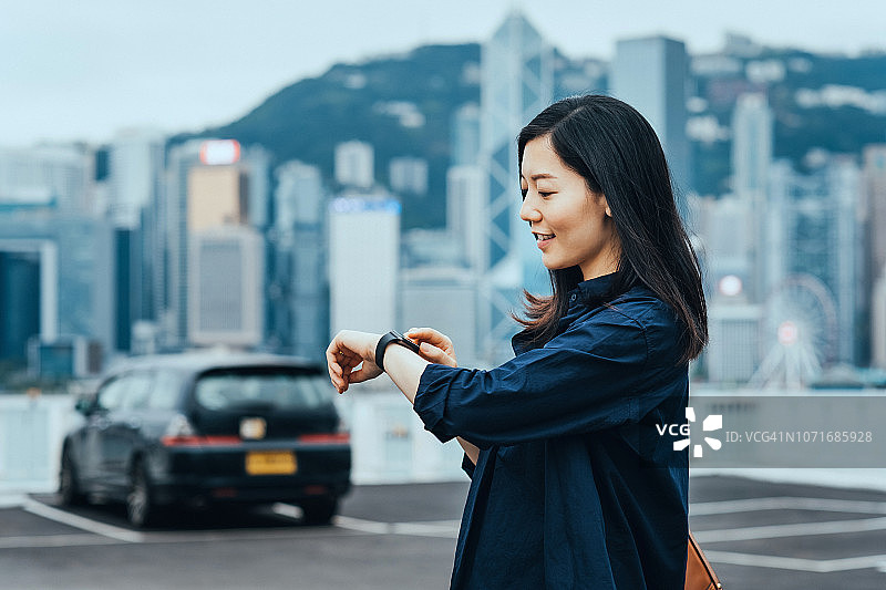 女人在城市户外停车场边走边用智能手表特写图片素材