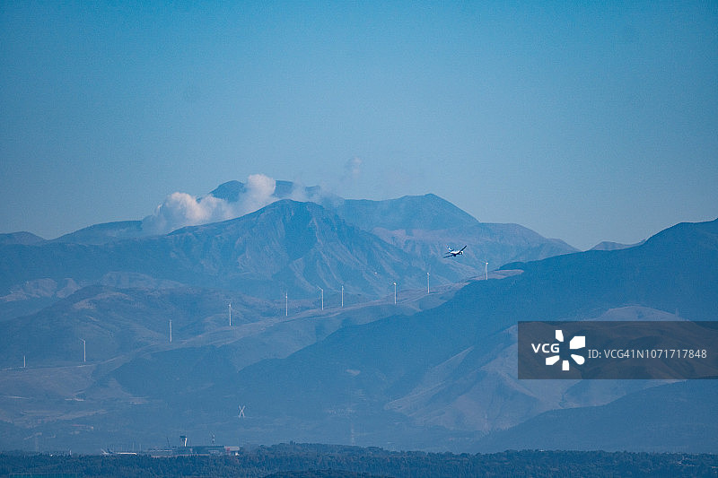 阿苏山和降落在日本阿苏熊本机场的飞机图片素材