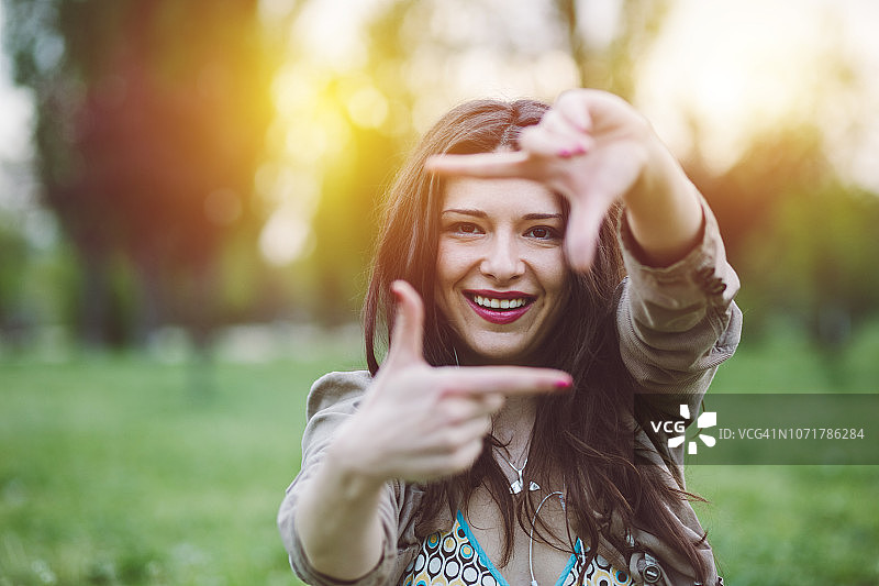 面带微笑，用手摆出边框造型的女人图片素材
