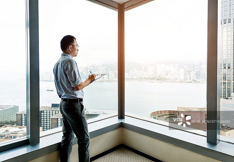 站在窗边写作的商人图片素材