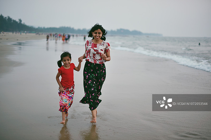 母女在沙滩上赤脚奔跑图片素材