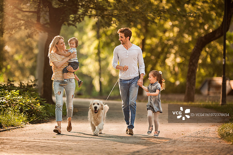 幸福家庭在春日与小狗玩耍图片素材