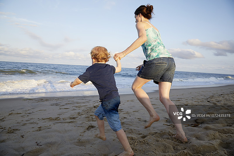 母子手牵手在海滩奔跑图片素材