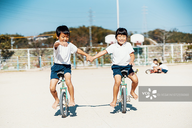 两名学龄前儿童手牵手骑独轮车图片素材