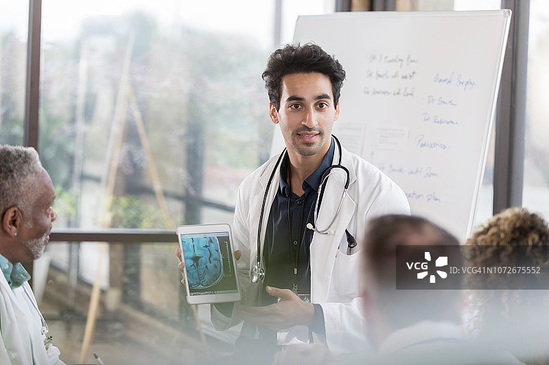 自信的男神经科医生与同事讨论患者的MRI图像图片素材