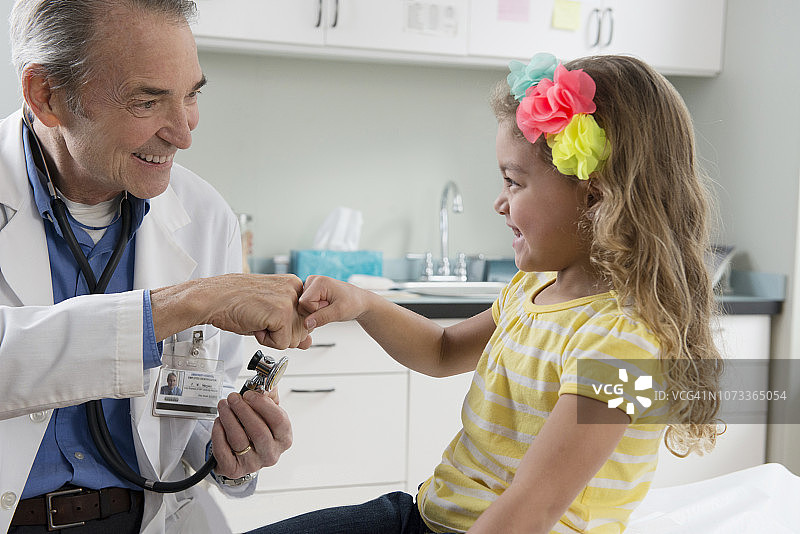 白种人儿科医生检查年轻女孩在诊所图片素材