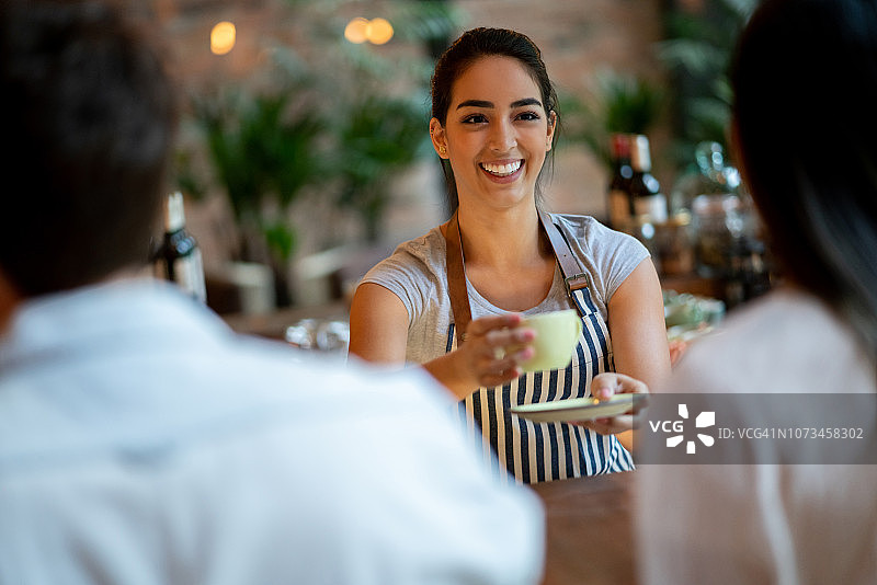 美丽女咖啡师微笑提供咖啡给顾客情侣图片素材